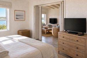 Coastal holiday home bedroom and adjoining lounge each with a TV and decoder, showing one satellite subscription set up for two rooms
